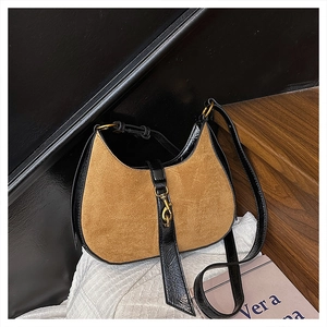 Detail of hobo bag featuring brown suede stitching with black leather and gold metal clasp