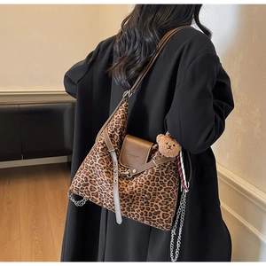 Detail of leopard print tote bag with brown leather flap and cute plush bear charm decoration