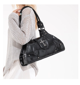 Close-up of black glossy moto bag featuring silver cross pendant and rivet accents