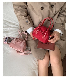 Close-up of mini suede Boston bags in wine red and pink with bow details and metal zippers