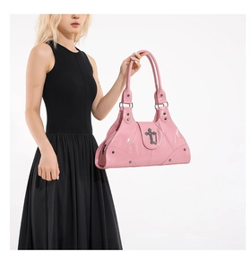 Detail of pink oil wax leather tote featuring a silver cross logo and metal chain accents