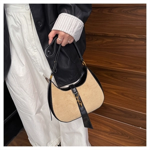 Detailed close-up of crescent hobo bag featuring beige suede and black textured leather