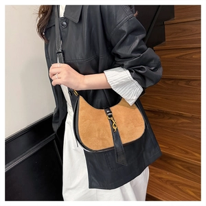 Detailed view of the tan suede crescent bag with black leather strap and gold metal clasp