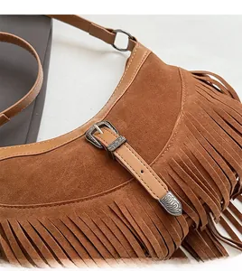 Gros plan sur un sac en daim marron avec boucle en métal vintage et détails de franges
