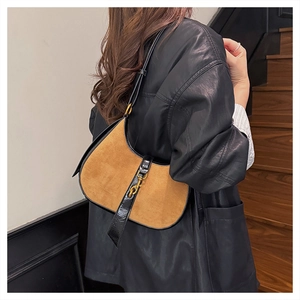 Detail view of brown faux suede crescent bag with black leather trim and gold buckle