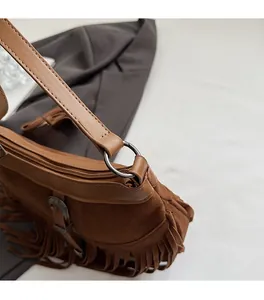 Détails d'un sac bandoulière vintage en daim marron avec longues franges et boucles en métal