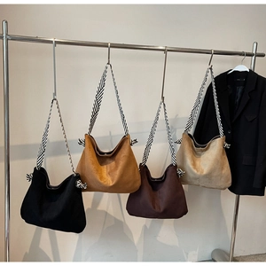 Detail of soft suede hobo bags in multiple colors with striped canvas shoulder straps