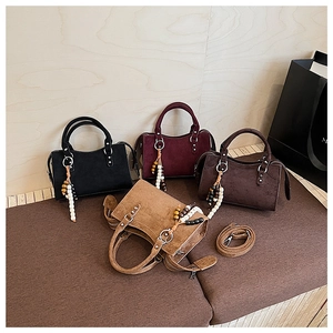 Detail of suede crossbody bags with wooden bead charms and detachable shoulder straps