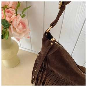 Détail du sac bohème en daim marron foncé avec des franges et des ferrures dorées