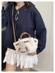 Dettaglio borsa in ecopelliccia bianca con manici in pelle e ciondolo a coniglio