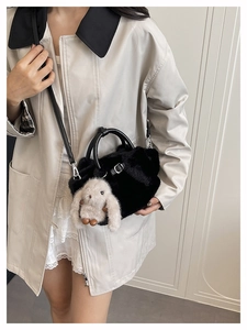 Dettaglio borsa a secchiello in peluche nera con ciondolo a coniglio bianco e tracolla in pelle