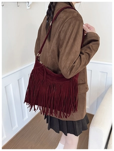 Détail du sac à bandoulière bordeaux à franges avec texture daim et boucles dorées