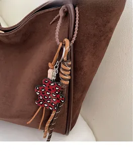 Close-up of leopard print bear charm on a dark brown suede tote bag handle