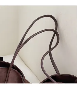 Detail view of the brown suede tote bag featuring long slender dual shoulder straps