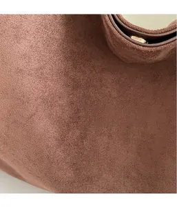 Detailed macro view of the brown suede fabric texture and gold magnetic buckle closure