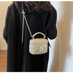 Detailansicht einer Tweed-Box-Tasche mit Kette und Pailletten auf einem schwarzen Mantel