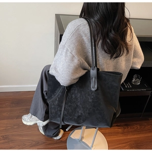 Detail of minimalist black large leather tote bag worn by model in lifestyle setting