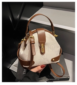 Close-up of cream canvas monogram handbag with brown leather trim and gold buckle