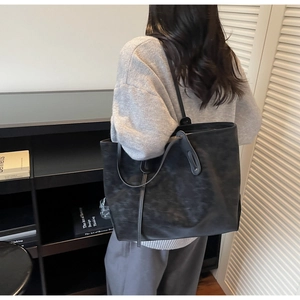 Detail view of large black leather tote bag with dual shoulder straps for commute