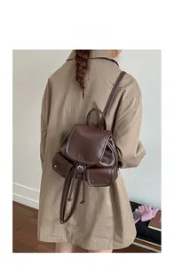 Detail of dark brown vintage backpack featuring white contrast stitching and bucket shape