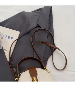 Detail of vintage beige floral fabric and brown leather crossbody bag with gold buckle