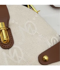 Close-up of jacquard fabric handbag with monogram pattern and gold metal clasp hardware