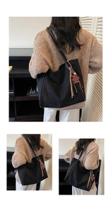 Close-up of black canvas tote bag with red leopard print charm and long fringe detail