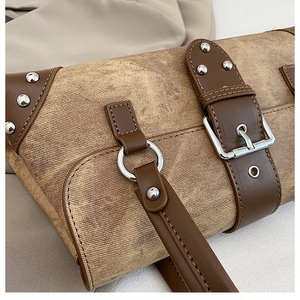 Close-up of vintage shoulder bag featuring distressed brown fabric and silver metal buckles
