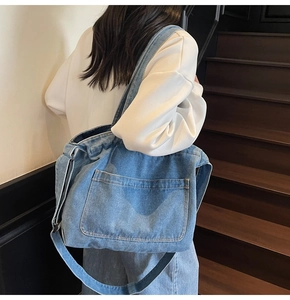 Detailed view of casual large capacity blue washed denim tote bag with front pocket on shoulder