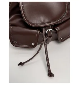 Detail of dark brown leather backpack featuring white contrast stitching and drawstring