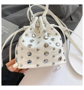 Detail of white bucket bag with silver metal studs and drawstring closure