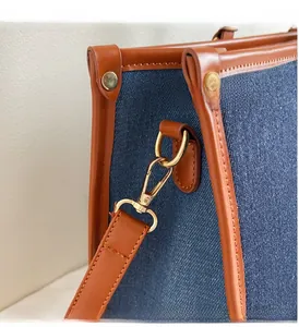 Detail of premium golden metal hook and leather trim on denim tote bag side