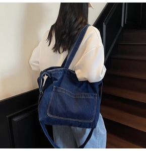Deep blue denim tote bag detail showing large front pocket and wide shoulder strap