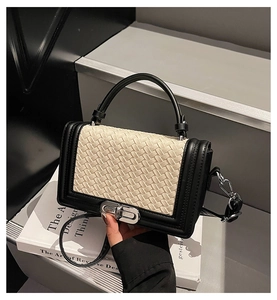 Détail du rabat en tissage blanc et du fermoir en métal argenté sur le sac noir