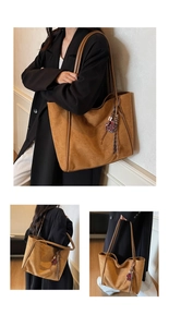 Detail view of large brown suede tote bag with woven charm on a black coat