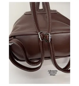 Detail of dark brown leather backpack with contrast stitching and silver adjustable buckle
