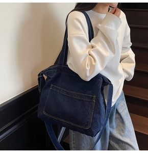 Detail of blue denim tote bag with visible stitching and long shoulder strap