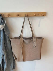 Minimalist khaki leather tote bag with retro matte texture hanging on wooden hook