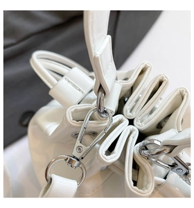 Close-up of silver metal hooks and premium white leather pleats on bucket bag