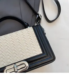 Détail de la texture tissée crème avec bordure en cuir noir et fermoir rotatif en argent