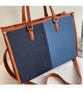 Close-up of contrast denim patchwork tote with leather handles and metallic studs
