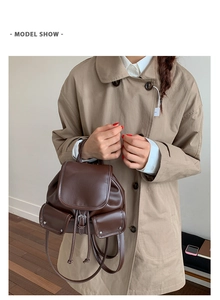 Model wearing a vintage dark brown leather backpack with buckle pockets and drawstrings