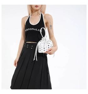 Close-up of white drawstring bucket bag with silver studs and chain strap