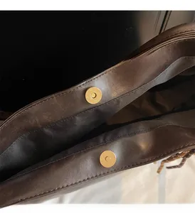 Detail of dark brown leather tote bag showing gold magnetic clasps and textured lining