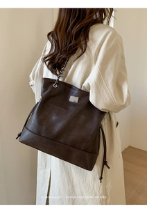 Close-up of vintage dark brown tote bag showing chain strap and faux leather texture
