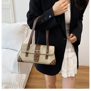 Detail view of canvas and leather shoulder bag featuring vintage buckle and metal studs