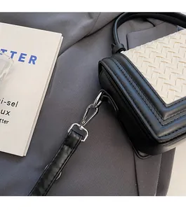 Détail du crochet métallique argenté et de la bandoulière en cuir d'un sac tressé