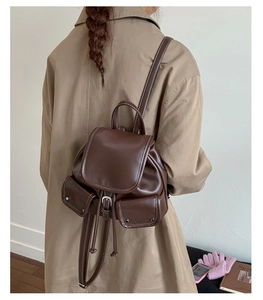 Detail of dark coffee vintage backpack featuring white contrast stitching and bucket drawstring