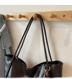 Detail of soft leather tote bag showing comfortable shoulder straps and metal ring accent