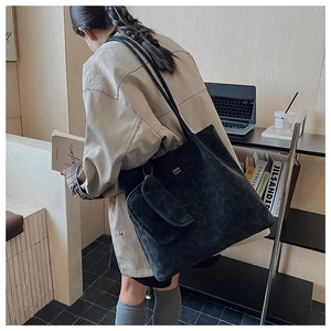 Dettaglio della borsa tote nera in velluto a coste con texture a righe e fregio dorato